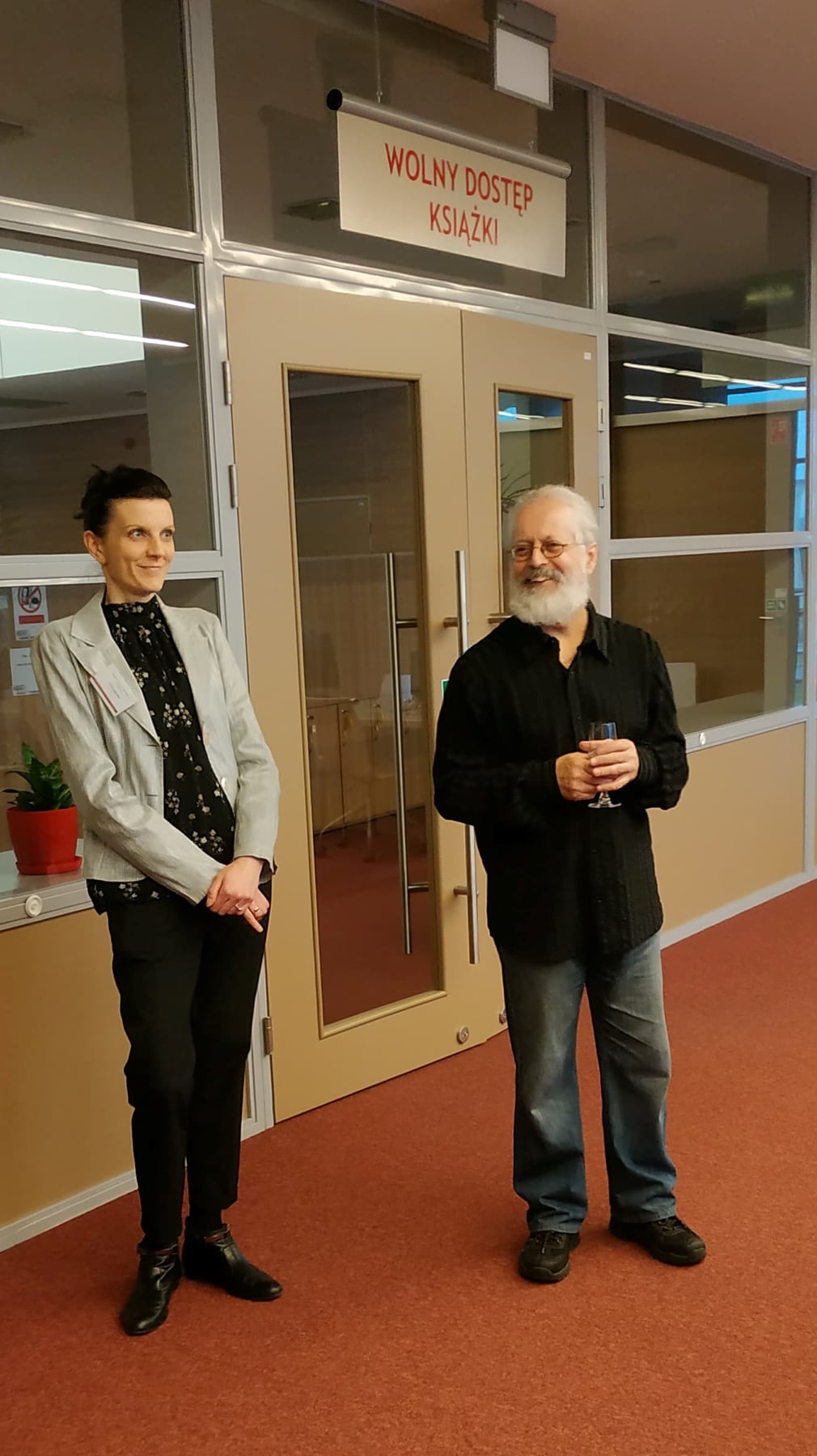 Wicedyrektor ds. Organizacji Informacji Naukowej Biblioteki Uniwersyteckiej w Kielcach oraz Jacek Dziubel stoją przed wejściem do wolnego dostępu do książek.