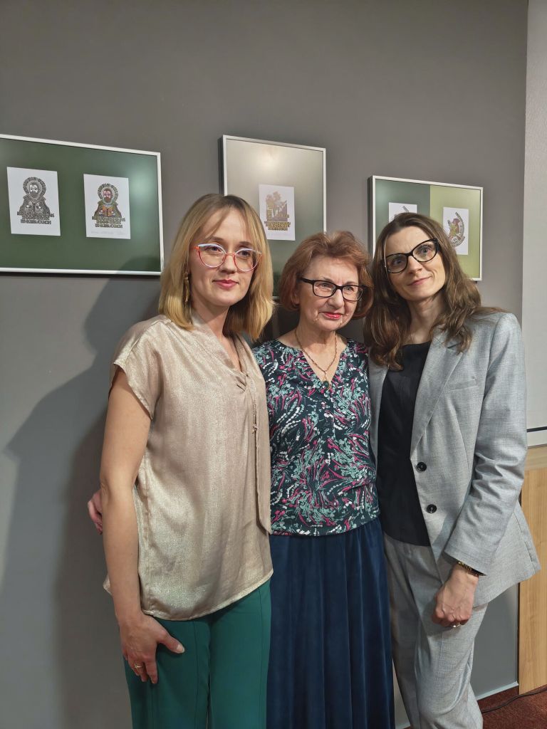 Uczestnicy pozują do wspólnego zdjęcia na tle ekspozycji 