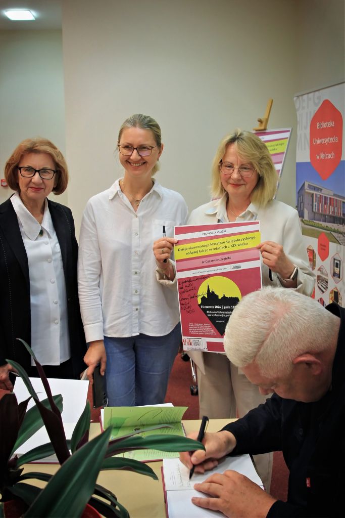Uczestnicy pozują z plakatem przy autorze